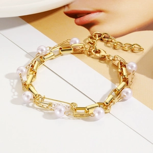 Detailed close-up of golden chain link bracelet featuring elegant pink pearls and lobster clasp