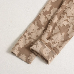 Détail du tissu caramel à fleurs 3D et des coutures de la manche sur la robe