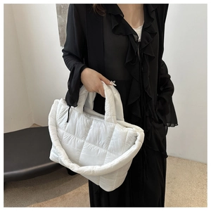 Detail of white quilted nylon dumpling tote bag featuring soft puffer texture and handles