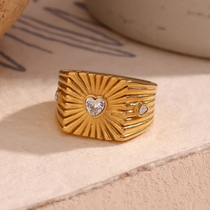 Macro view of wide gold-plated ring featuring heart zircon and radial engraved patterns