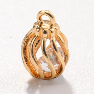 Detailed view of golden hollow birdcage charm with transparent cubic zirconia stone inlay