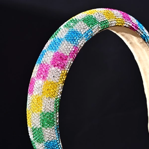 Close-up of a wide rhinestone headband with multi-colored crystals on a black background