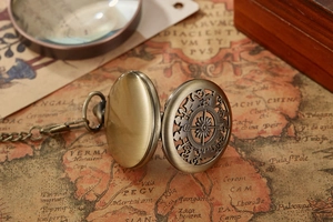 Close-up of a vintage bronze compass pocket watch on an old antique world map background