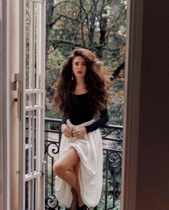 Detail of slim black top and cream midi skirt with puff sleeves in autumn garden setting