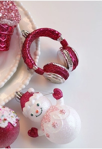 Detail of glittery pink Christmas ornaments featuring cupcake and earphone shapes