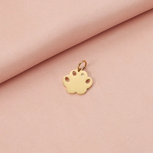 Detailed macro view of golden paw print pendant with a sparkling crystal on pink fabric