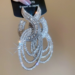 Detailed macro view of multilayered geometric silver dangle earrings with shiny crystals