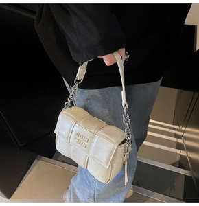 Détail d'un sac bandoulière matelassé beige avec une grosse bandoulière en chaîne argentée