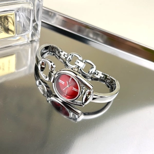 Detailed view of red dial women's bracelet watch with silver horsebit metal chain links