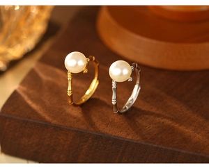Detail of bamboo joint style rings in gold and silver with lustrous pearls on wood