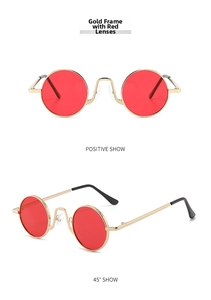 Detail view of retro small round sunglasses with gold metal frames and red lenses
