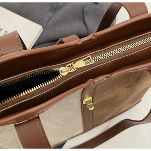Detailed macro of the metal zipper closure and gold buckle on a brown leather tote bag