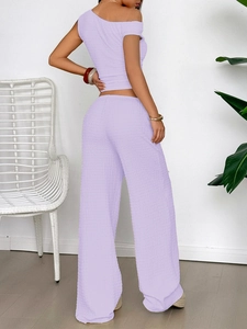 Detail of purple textured one-shoulder top and wide-leg pants on a model back view