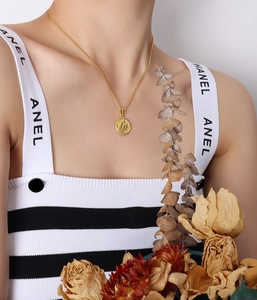 Detail of vintage oval pendant necklace with embossed wing texture and gold finish