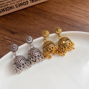 Detail of vintage Jhumka bell tassel earrings in gold and silver finish on ceramic tray