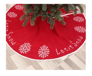 Detail of red knitted Christmas tree skirt with white snowflakes and Let it Snow text