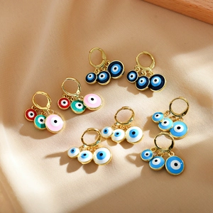 Detail of bohemian gold hoop earrings with colorful devil eye charms on silk fabric