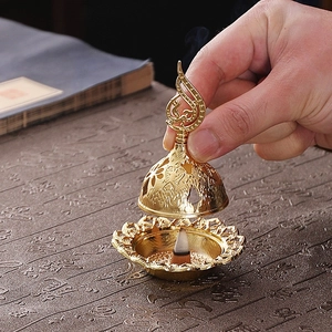 Detail of handheld antique gold incense burner lid with intricate hollow patterns