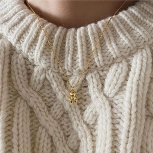 Close-up of a 3D teddy bear pendant necklace paired with a cozy white knit sweater