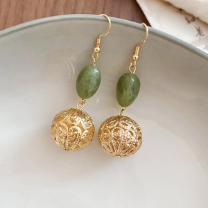 Détails des perles en résine verte et boules en métal doré évidé sur boucles d'oreilles