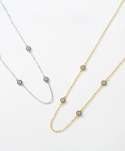 Macro detail of gold and silver S925 necklaces with blue evil eye charms and zircon inlay