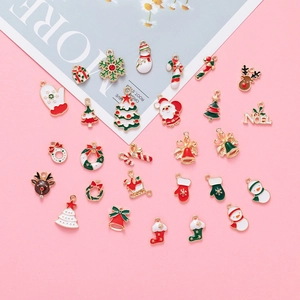 Flat lay of colorful Christmas alloy charms including snowman and Santa on pink background