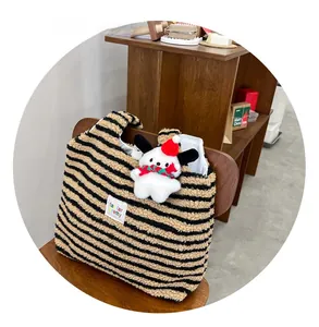 Detail of striped plush tote bag with cute puppy doll ornament on wooden chair