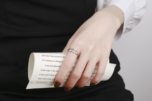 Detailed view of silver hands heart gesture ring worn on finger for a stylish look