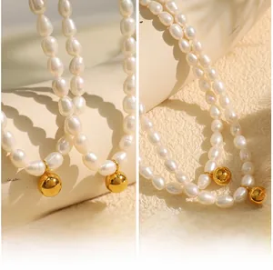 Detail of baroque freshwater pearl necklace with polished gold bead on stone surface