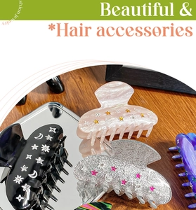 Detail of star and moon hair claws in black, pink, silver, and purple galaxy designs