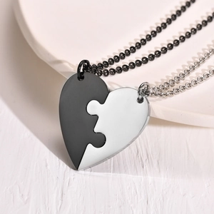 Close-up of black and silver titanium steel heart puzzle necklaces for friendship on a tray