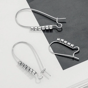 Silver safety pin earrings with square rhinestones set on a black and white background