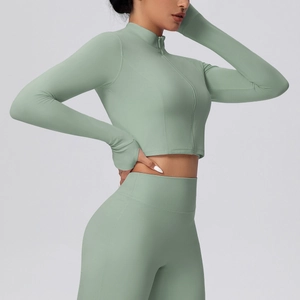 Dettaglio del top da yoga verde salvia con fori per i pollici e leggings a vita alta