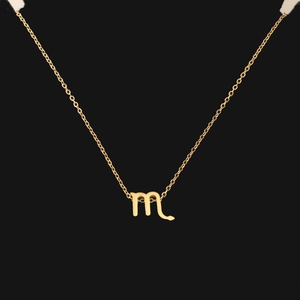 Macro shot of gold Scorpio constellation pendant with letter M on a fine chain