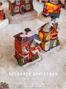 Detail of lit Christmas resin miniature houses with snow and warm LED lights