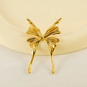 Polished gold butterfly wing stud earrings with minimalist aesthetic on beige podium