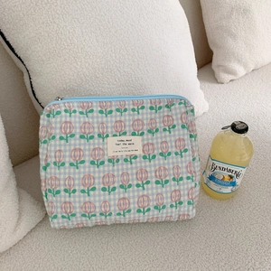 Close-up of quilted floral cosmetic bag with light blue tulip patterns and soft cotton texture