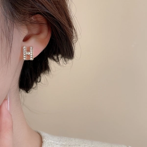 Close-up of gold luxury H-shaped earrings with shimmering pave-set white zirconia stones