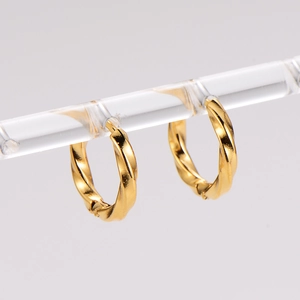 Detail of elegant gold twisted hoop earrings hanging on a clear display stand