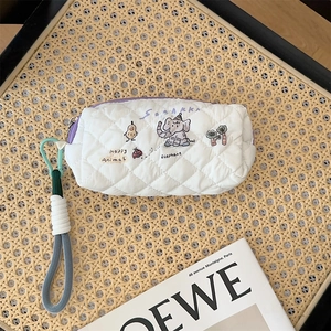 Macro view of white quilted pencil case with colorful animal prints and woven wristlet