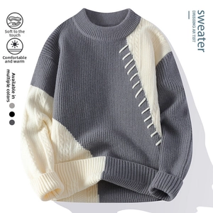 Detailansicht der Zopfmuster-Textur und weißen Ziernähte auf einem grauen Pullover