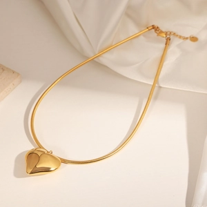 Elegant gold heart pendant necklace with a sleek snake chain on soft silk fabric
