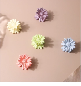 Macro view of five colorful daisy hair clips with glossy finish and spring detail