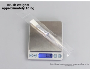 Flat fiber facial mask brush with clear handle weighing 10.8g on a digital scale