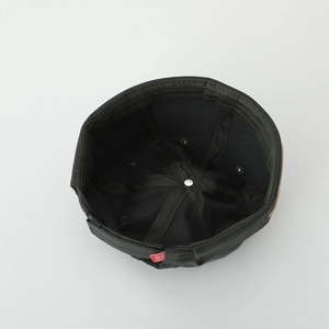 Close-up of internal stitching and metal top button of the green kid's docker hat