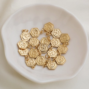 Macro view of 14K gold plated hexagonal pendants with moon and star motifs in a ceramic bowl