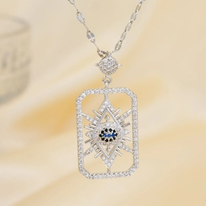 Macro shot of silver geometric square evil eye pendant with blue zircon on yellow silk