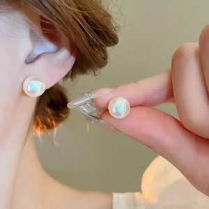 Macro shot of mermaid pearl earrings with iridescent gold-plated finish on ear