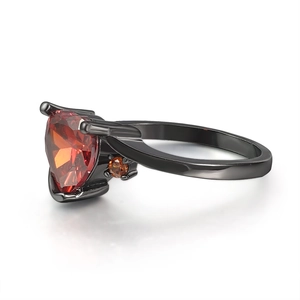 Macro detail of black gold ring featuring heart-shaped orange zircon and side stones