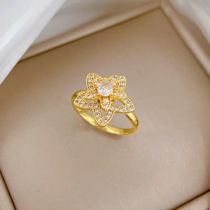 Eleganter goldener doppelter Blumenring mit funkelnden Zirkonsteinen auf Seidenhintergrund
